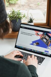 Person typing on a laptop displaying the Shopify homepage near a window plant, demonstrating how AI is changing digital marketing.